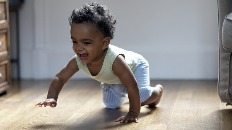 Black baby smiling and crawling on floor