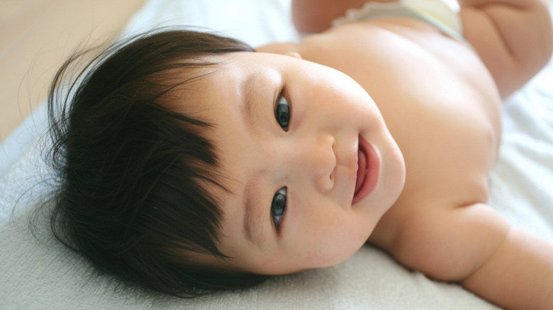 Asian baby lying on back and smiling at camera