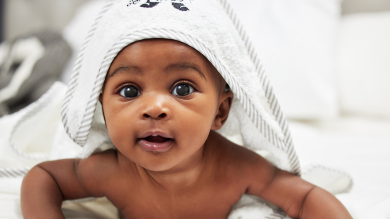 Black baby with towel on head pushing up from stomach