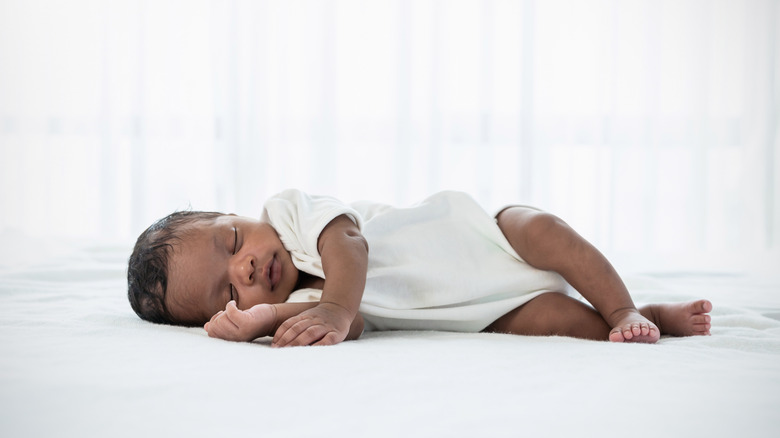 A sleeping newborn baby rests on her side