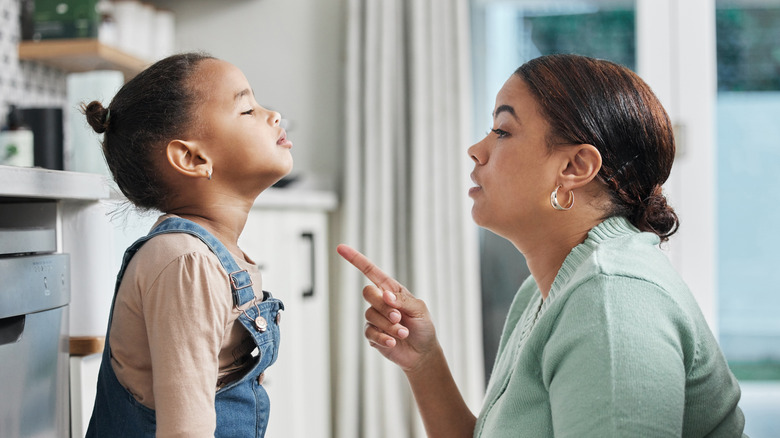 An adult holds her finger up to a child with a stern expression on her face