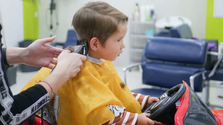 Boy getting haircut in toy car