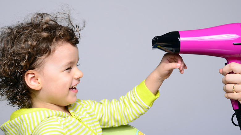 Parent playing with hairdryer with toddler boy