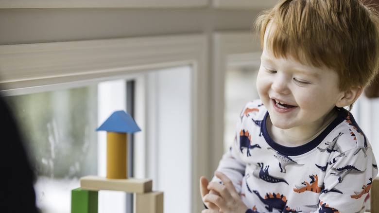 little boy laughing while playing with blocks