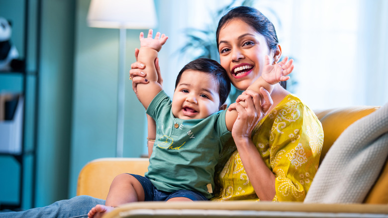 young mom playing with baby boy on sofa