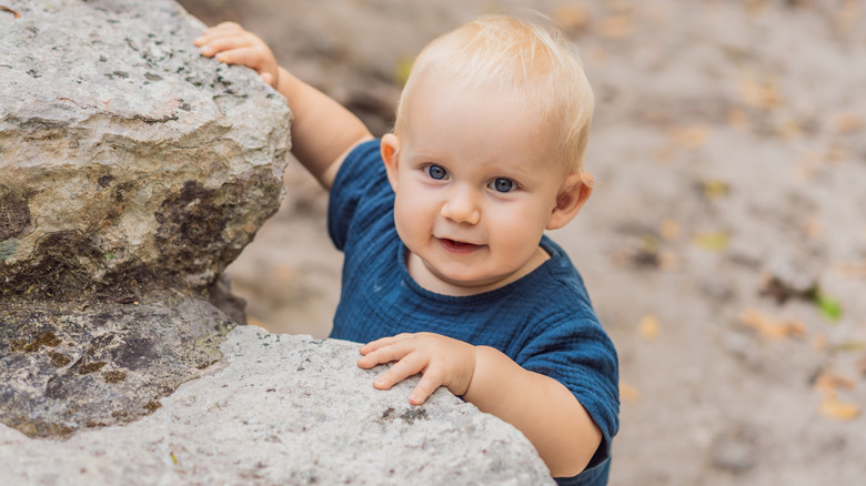 little boy playing around rocks while outside
