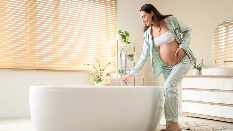 Pregnant woman in front of bath tub