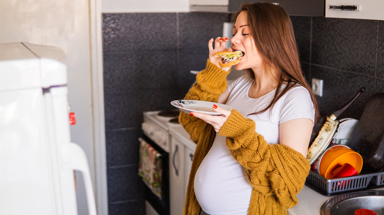 Pregnant woman eating in kitchen