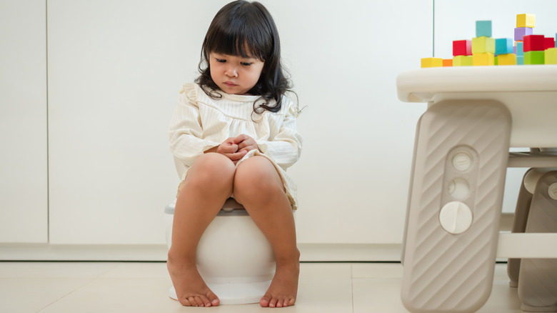 Girl in white outfit sitting on potty seat