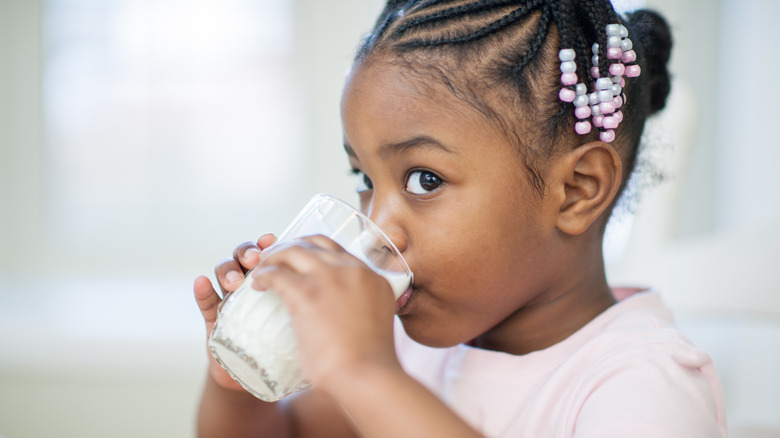 Girl toddler with braids drinking milk