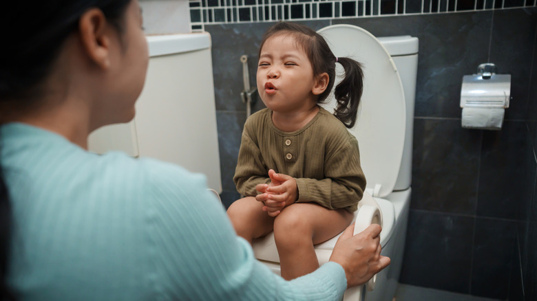 Mom with girl sitting on toilet seat