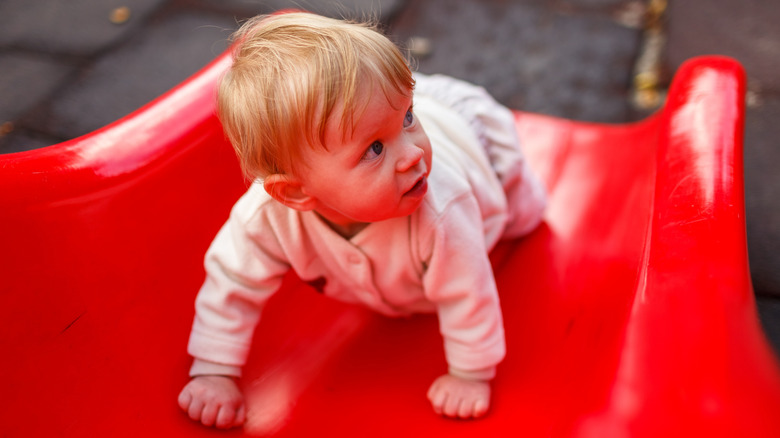 Baby crawling on a red slide