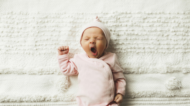 Baby girl yawning in a pink outfit
