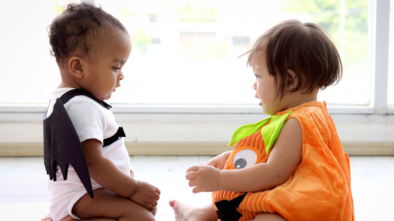 Baby girl dressed like pumpkin and baby boy with vampire wings