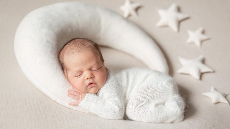 Baby sleeping on a moon next to stars