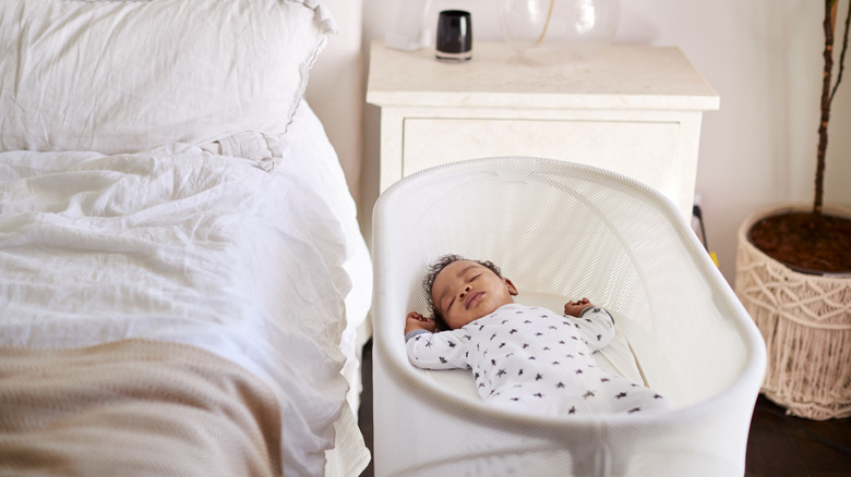 A baby sleeps in a bedside bassinet