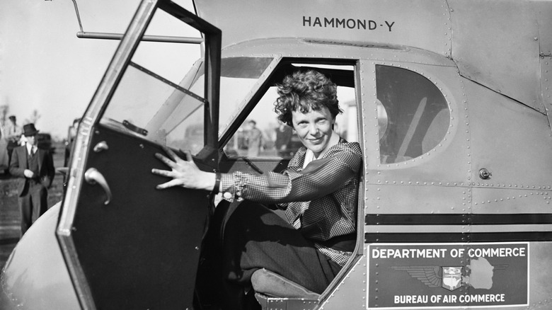 Amelia Earhart inside a government airplane holding the door open