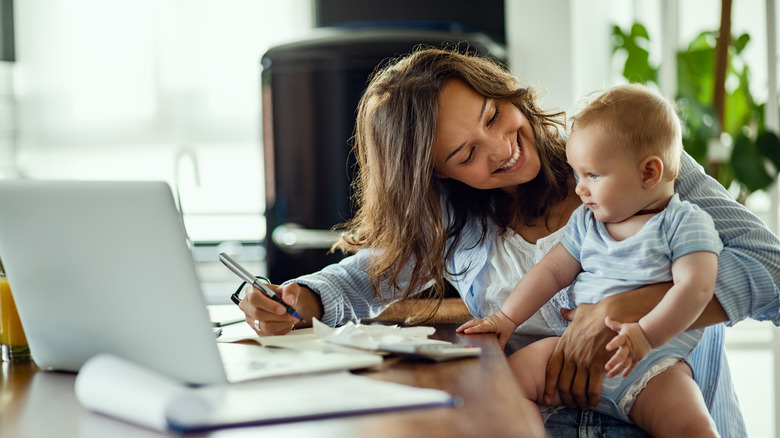 A mom holds her baby while filling out forms