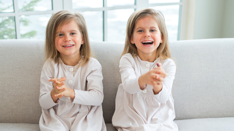Twin girls in white smiling on couch
