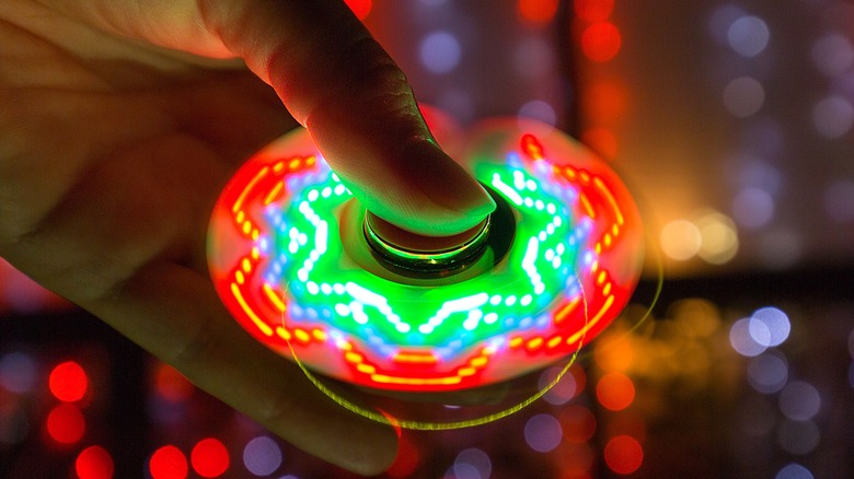 Hand holding multi-colored LED fidget spinner