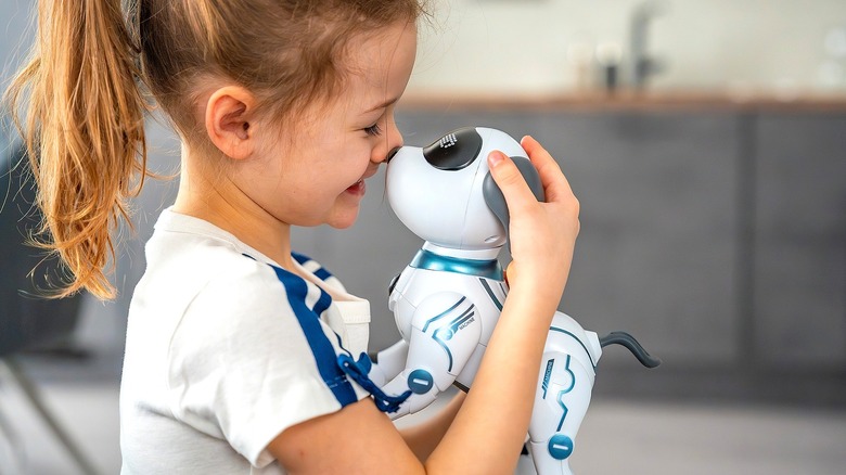 Young girl with her eyes closed holding a smart toy dog up to her nose