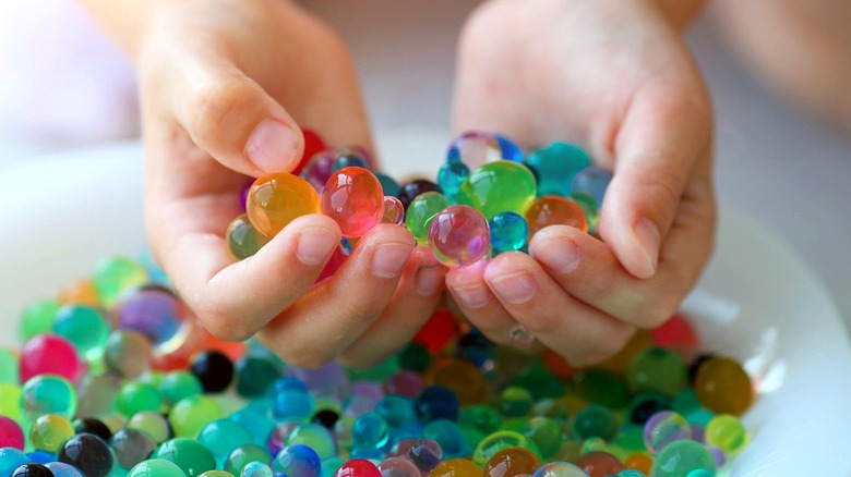Two hands holding colorful water beads