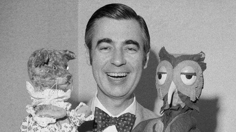 Fred Rogers smiling holding Henrietta Pussycat and X the Owl