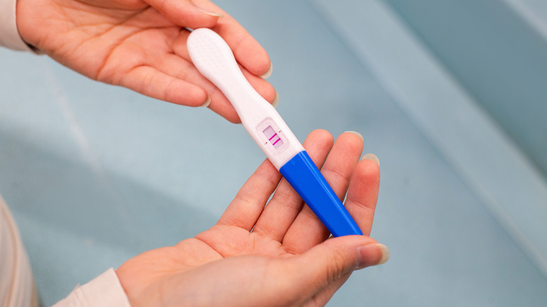 person holding a pregnancy test with two lines