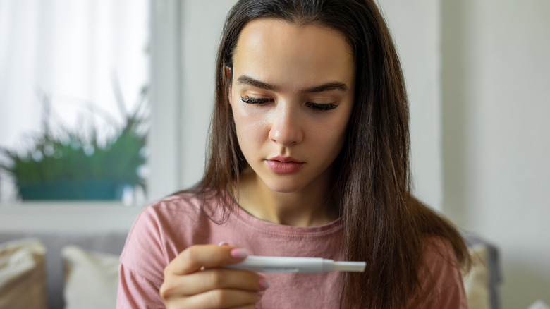 woman looking down at a pregnancy test