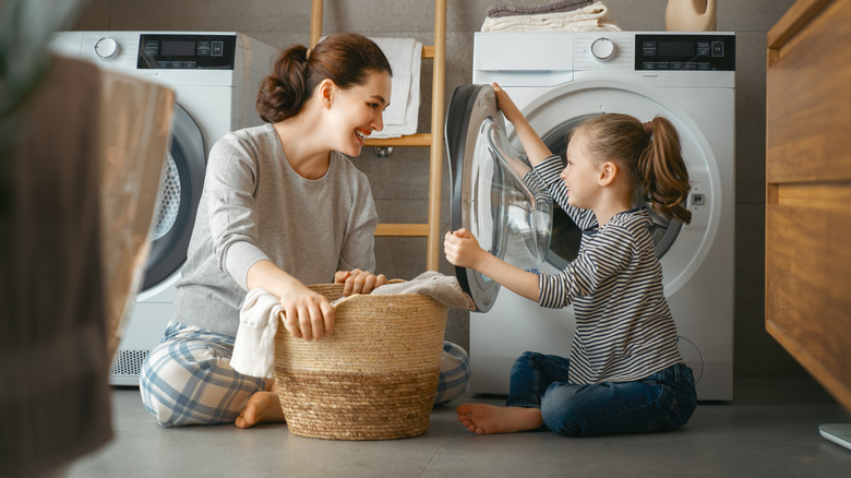 mom and daughter smiling and doing laundry together