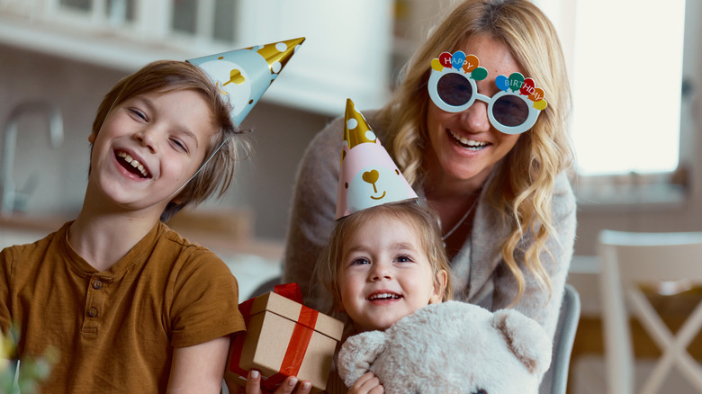 Mother and two children wearing birthday props and laughing