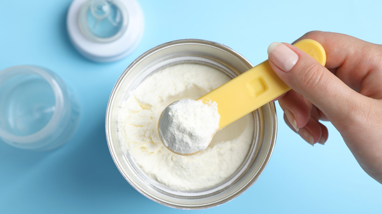 Person scooping out formula from a can