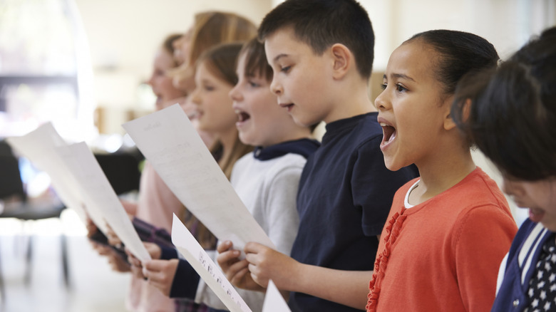 Kids standing in a line practicing singing for a choir