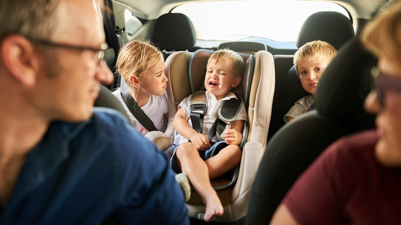 A family on a road trip tries to comfort at the youngest child who is upset