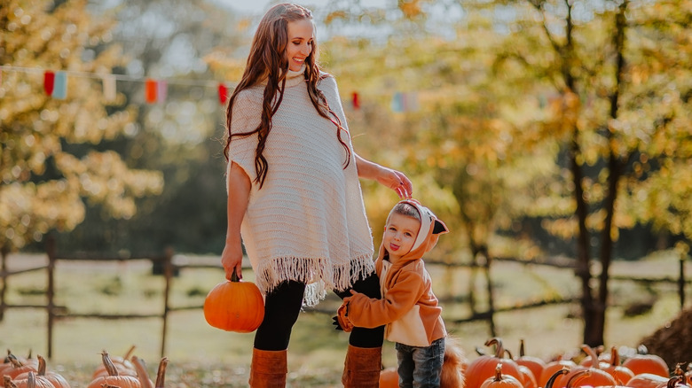 pregnant woman and older child in pumpkin patch