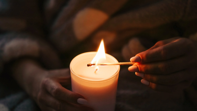 photo of woman lighting a candle