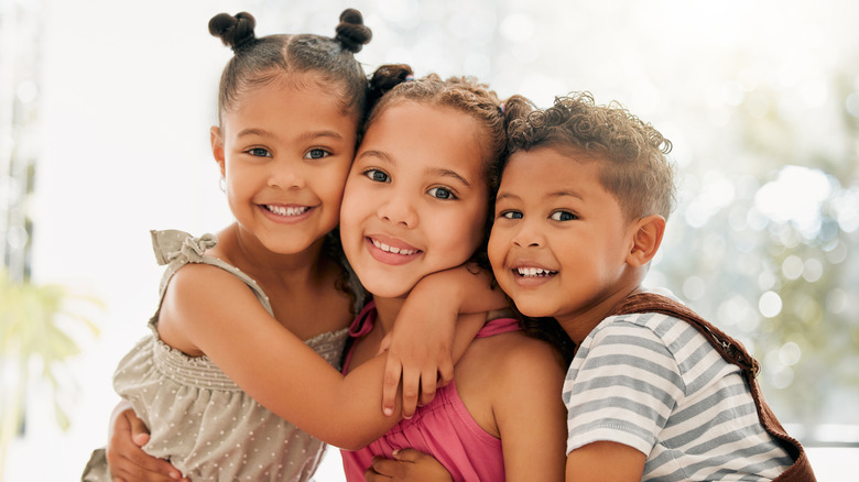 Two young sisters and brother hugging