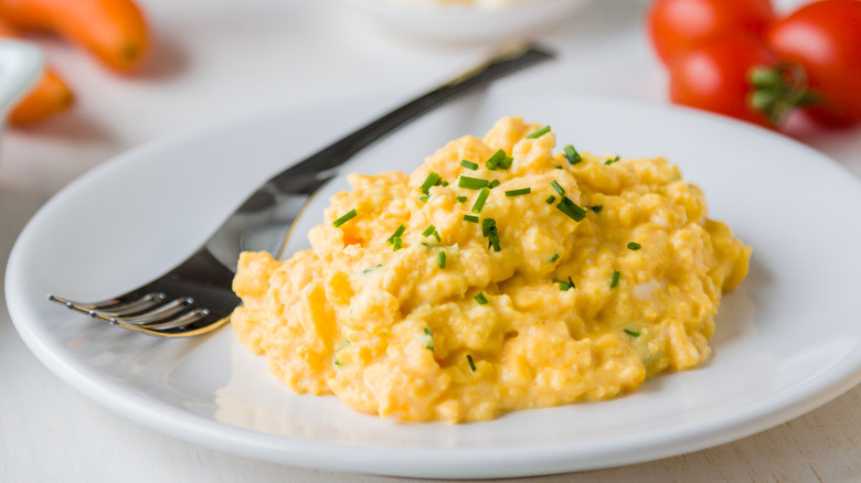 A plate of scrambled eggs with a fork
