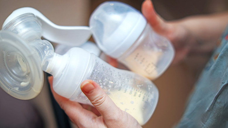 mom holding a breast pump in one hand and a bottle in the other