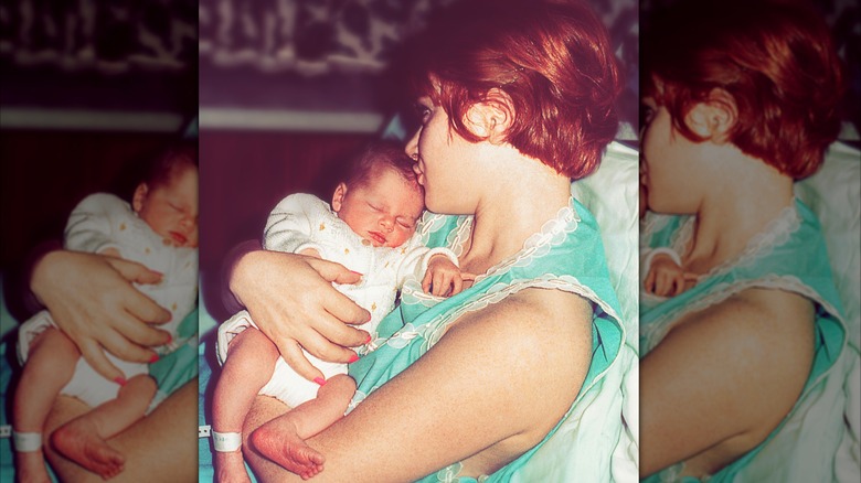 1970s woman holding and kissing infant