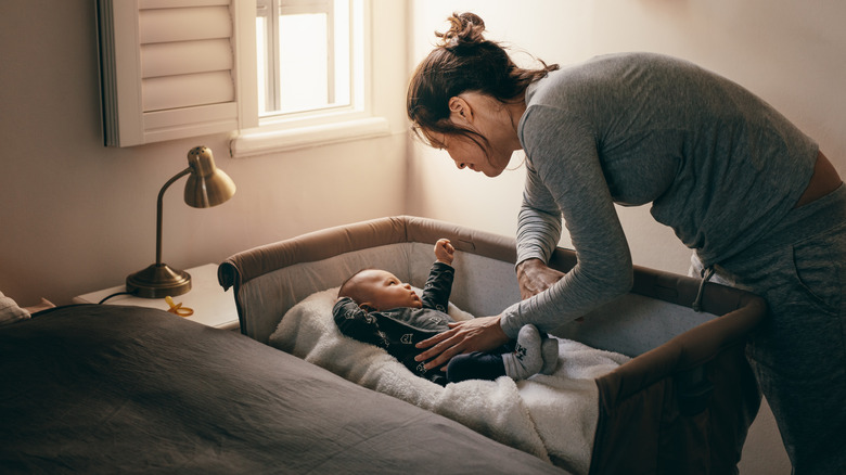 woman putting baby into a co-sleeper bassinet