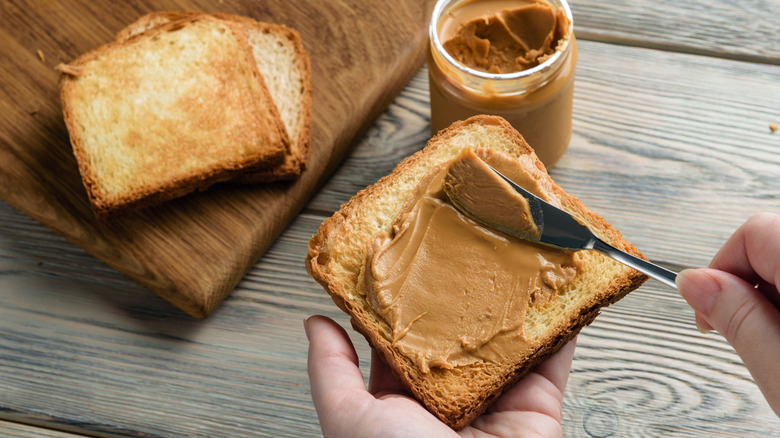 Person spreading peanut butter on toast