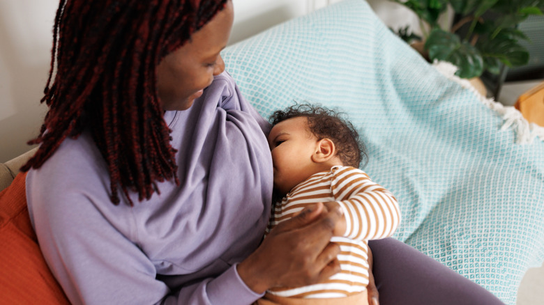 A mother holds her 6-month-old as he nurses