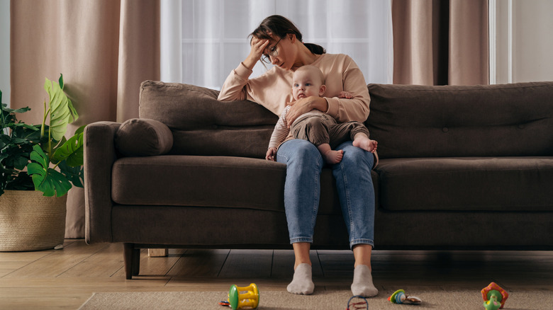 Tired father sits with his upset baby on the floor