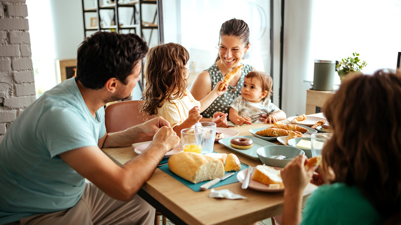A family enjoys breakfast at home with three kids of various ages