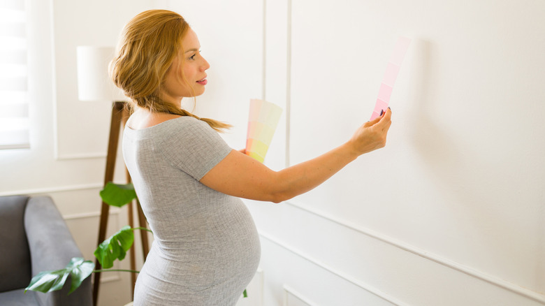 a pregnant woman looks at paint chips