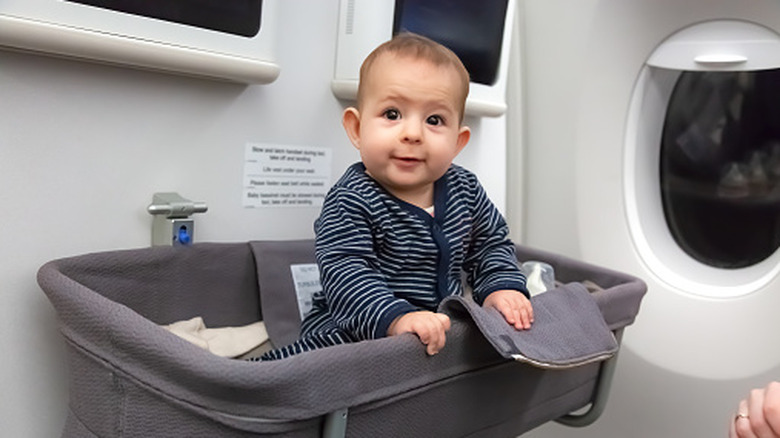 Baby sitting up in bassinet on plane