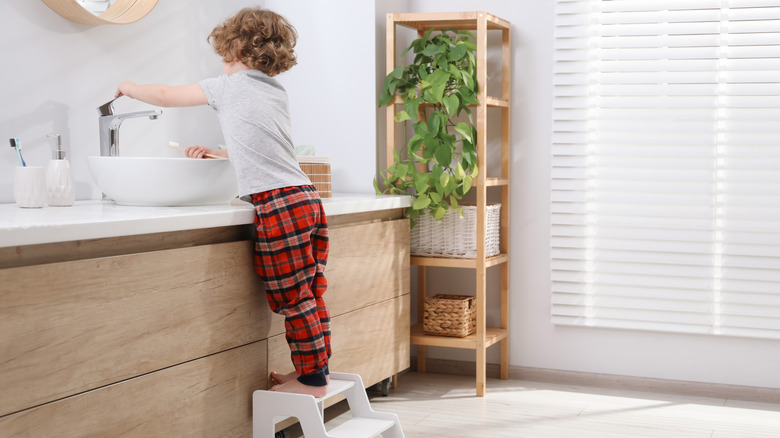 Child using a step stool in a bathroom