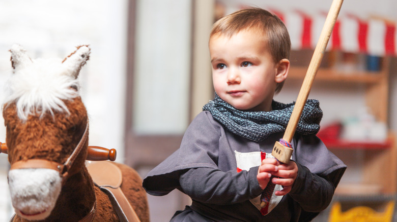 little boy dressed as a knight with a rocking horse