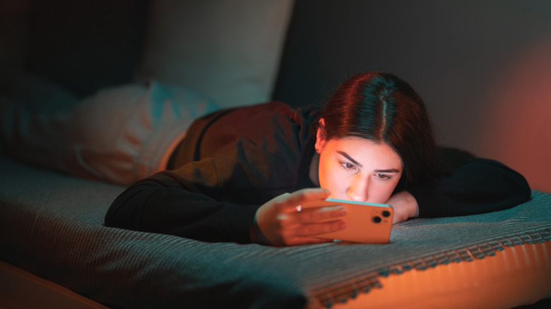 Teen girl holding her phone on the bed